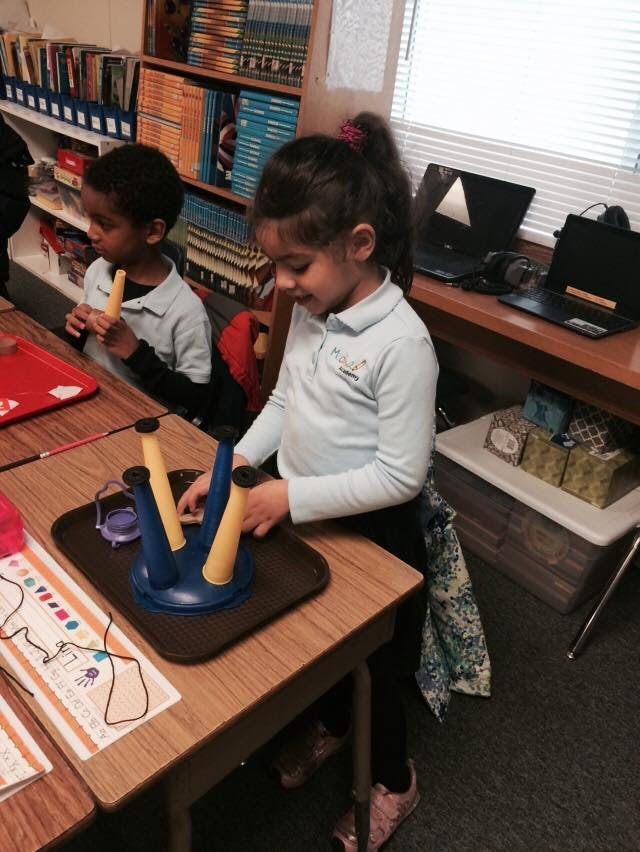Child assembling a toy on a desk in a classroom