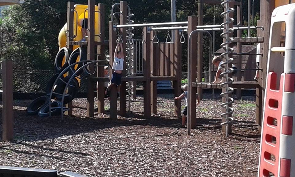 Child hanging upside down from monkey bars on a playground