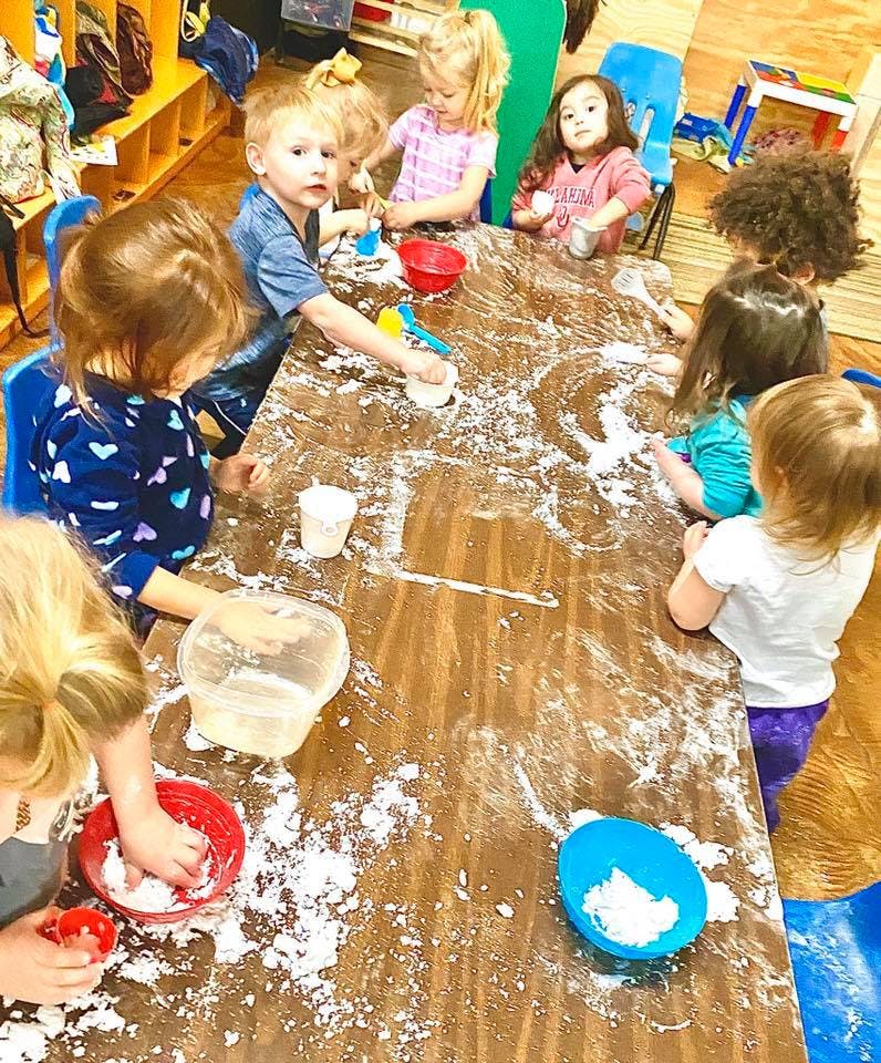 Children playing with white powder on a large table