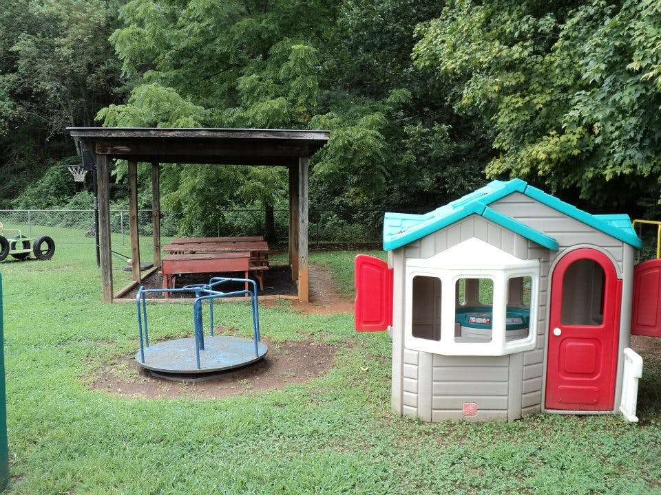 Playground with a small playhouse, merry-go-round, and covered picnic area