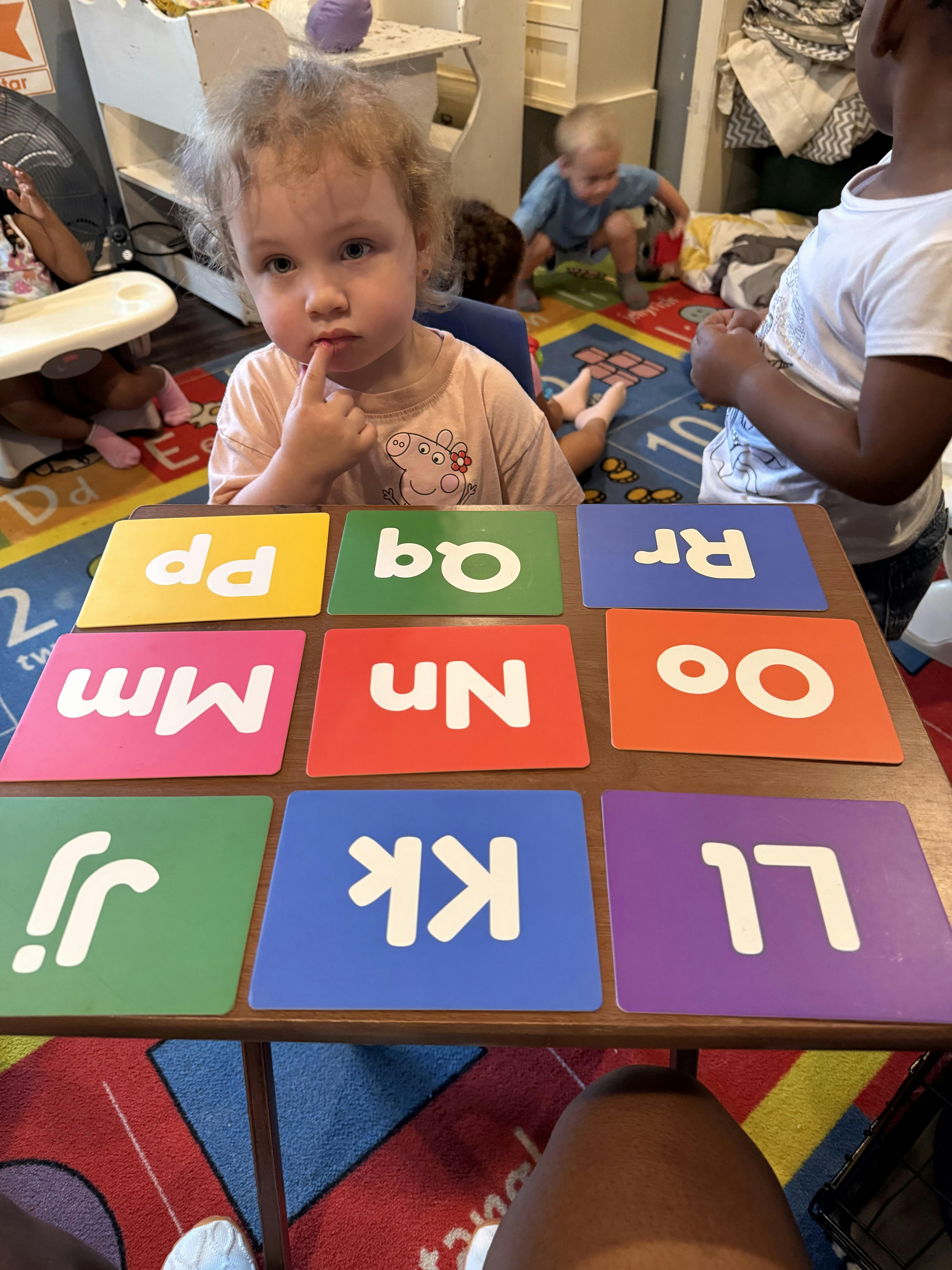 Child looking at a table with colorful alphabet cards