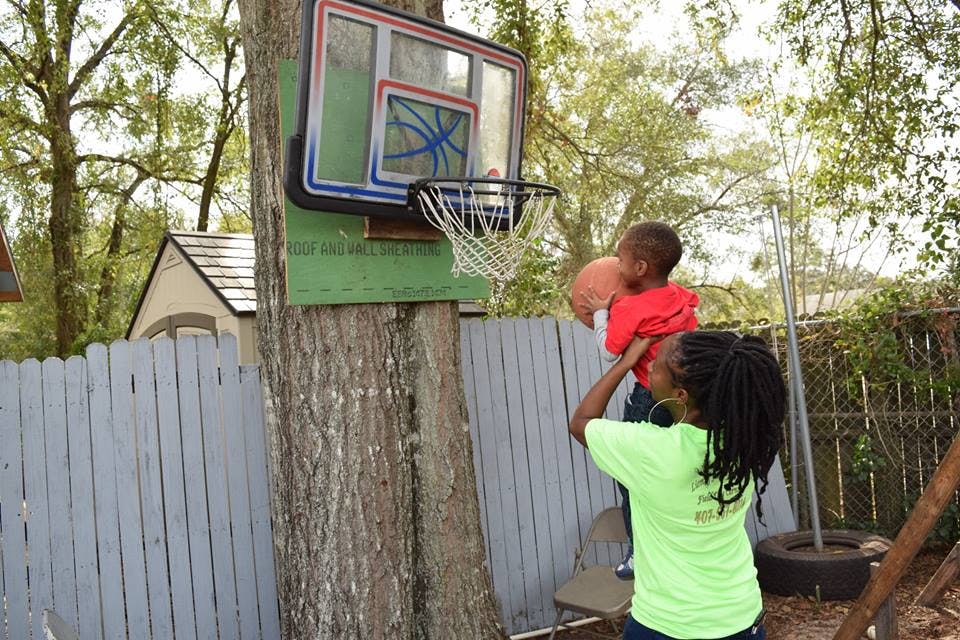 Person holding a child up to a basketball hoop