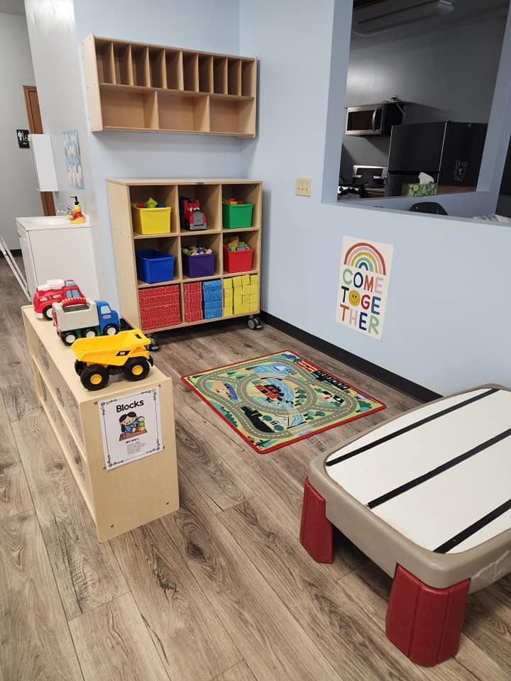 Playroom with toy trucks, storage shelves, and a small rug
