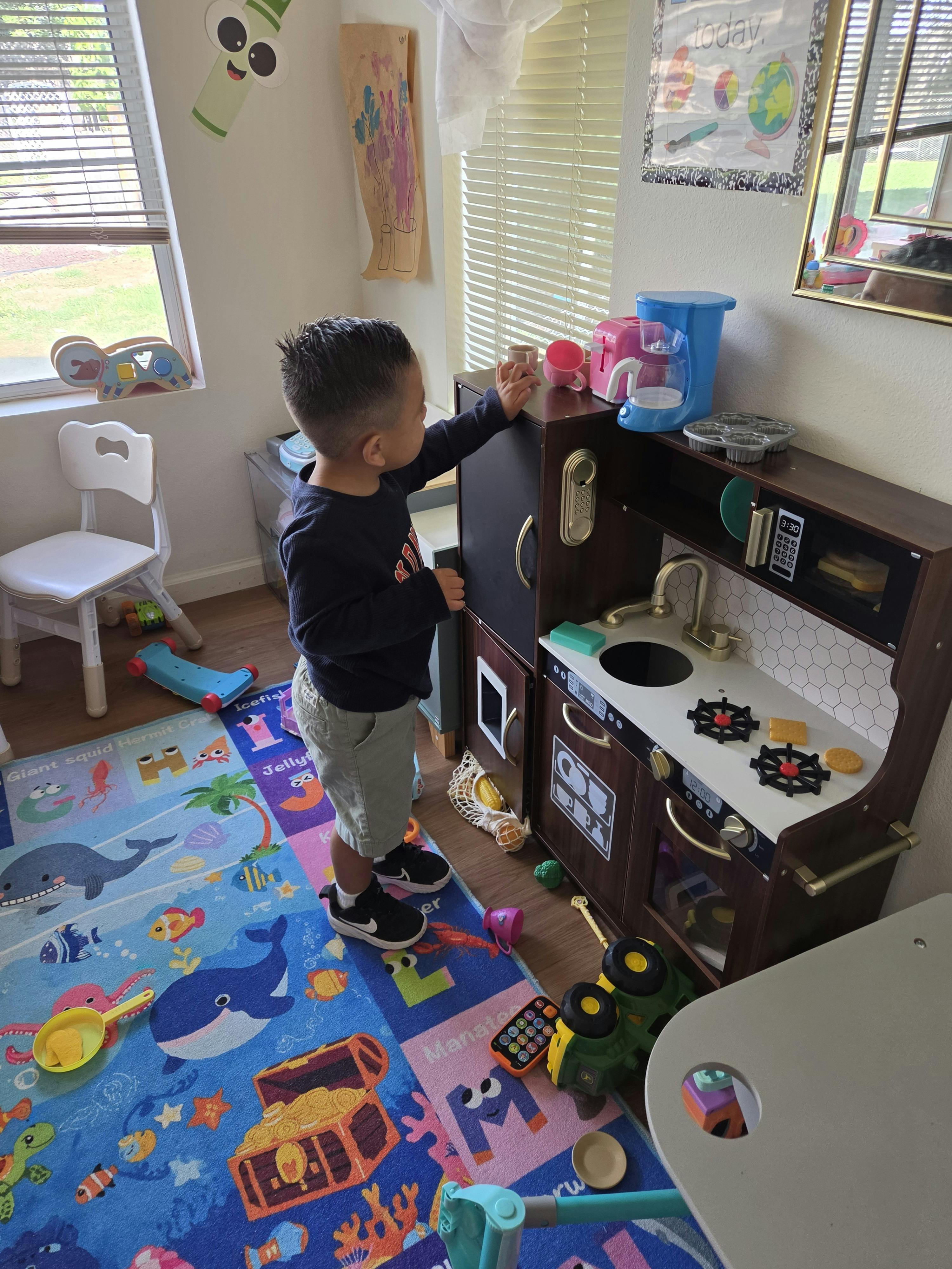 Child playing with a toy kitchen in a playroom