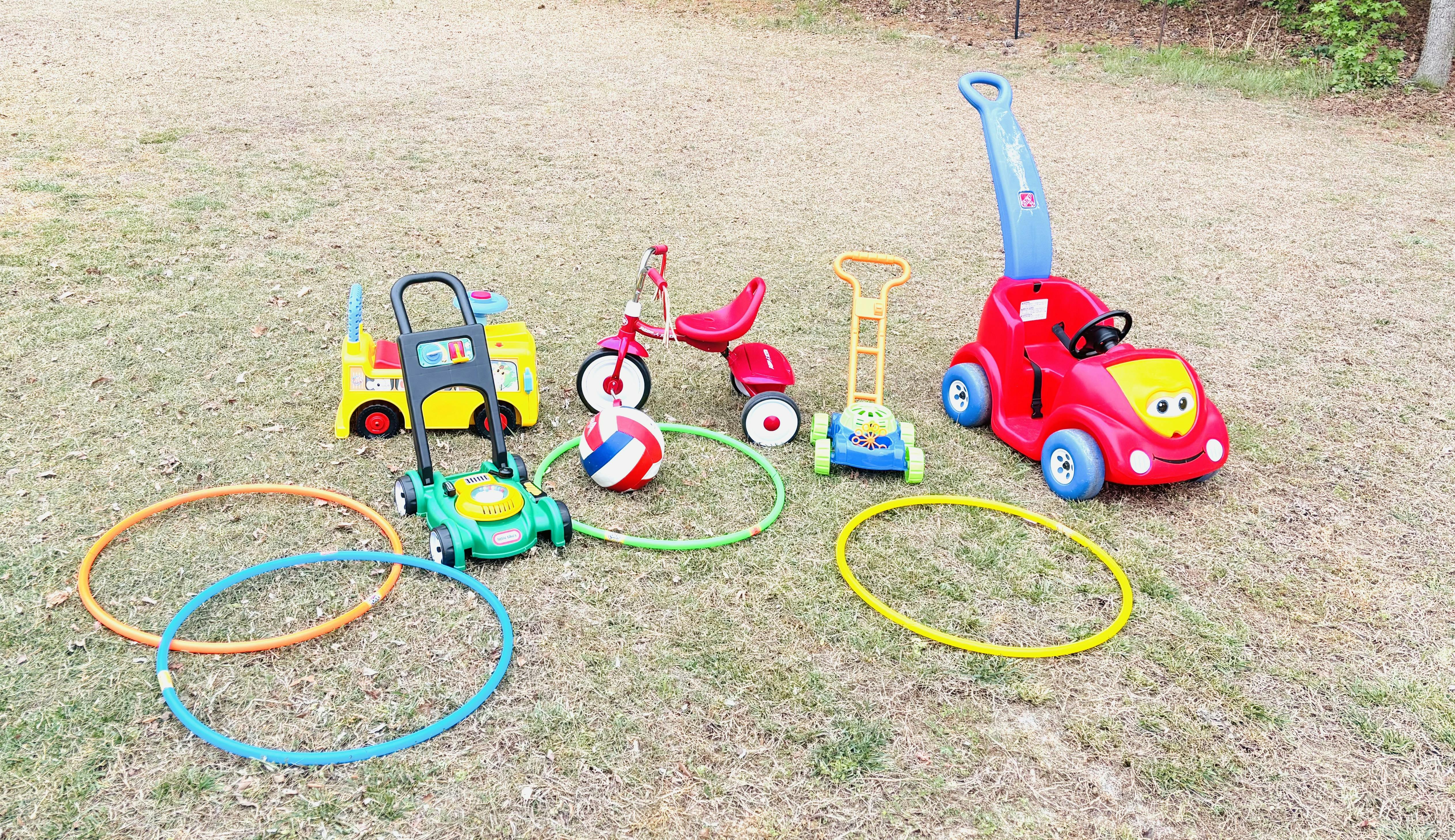Children's ride-on toys, including a red car, yellow bus, and red tricycle