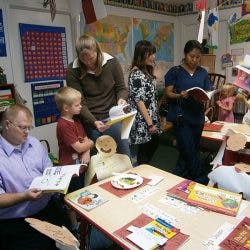 Adults and children reading books in a classroom