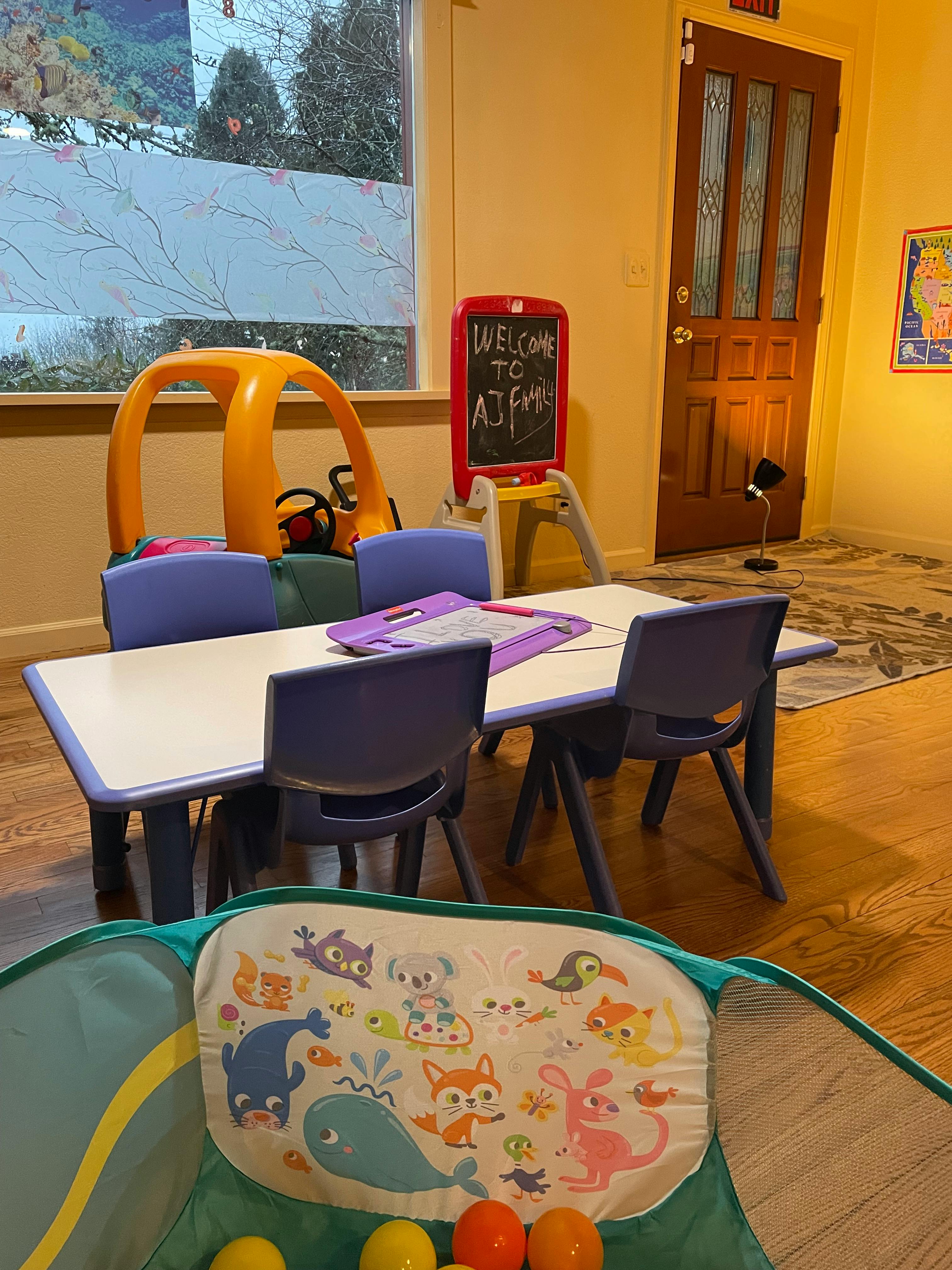 Children's play area with small table and chairs, toy car, and chalkboard