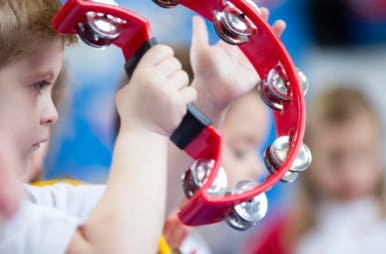Child holding a red tambourine
