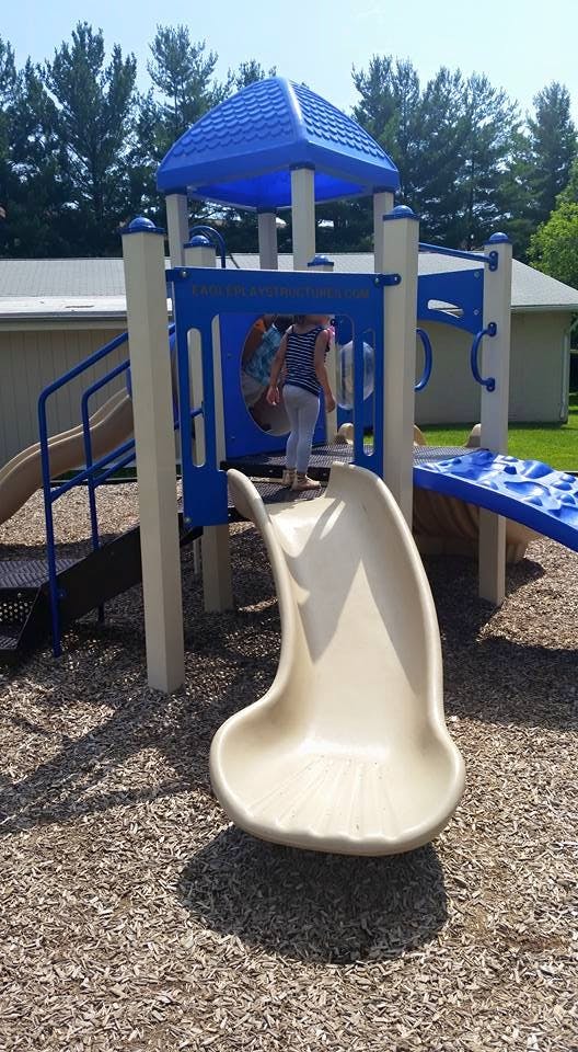 Child on a playground structure about to go down a slide