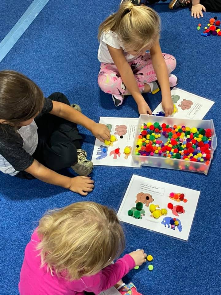 Children playing with colorful pom-poms and animal-shaped cutouts