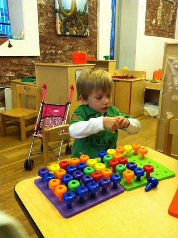 Child playing with colorful pegboard toys at a table