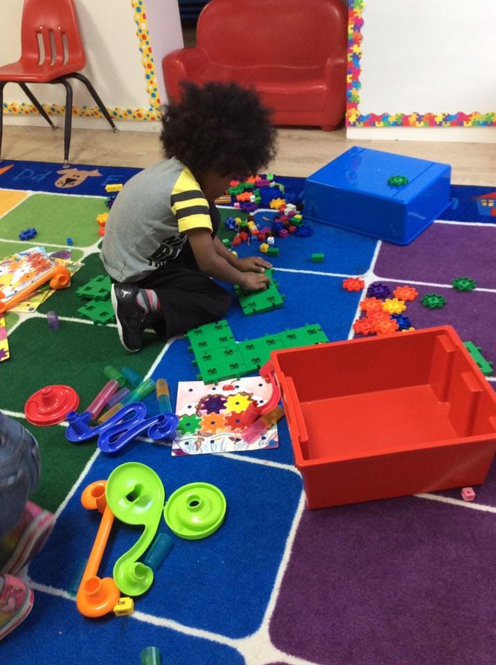 Child playing with building blocks on a colorful rug