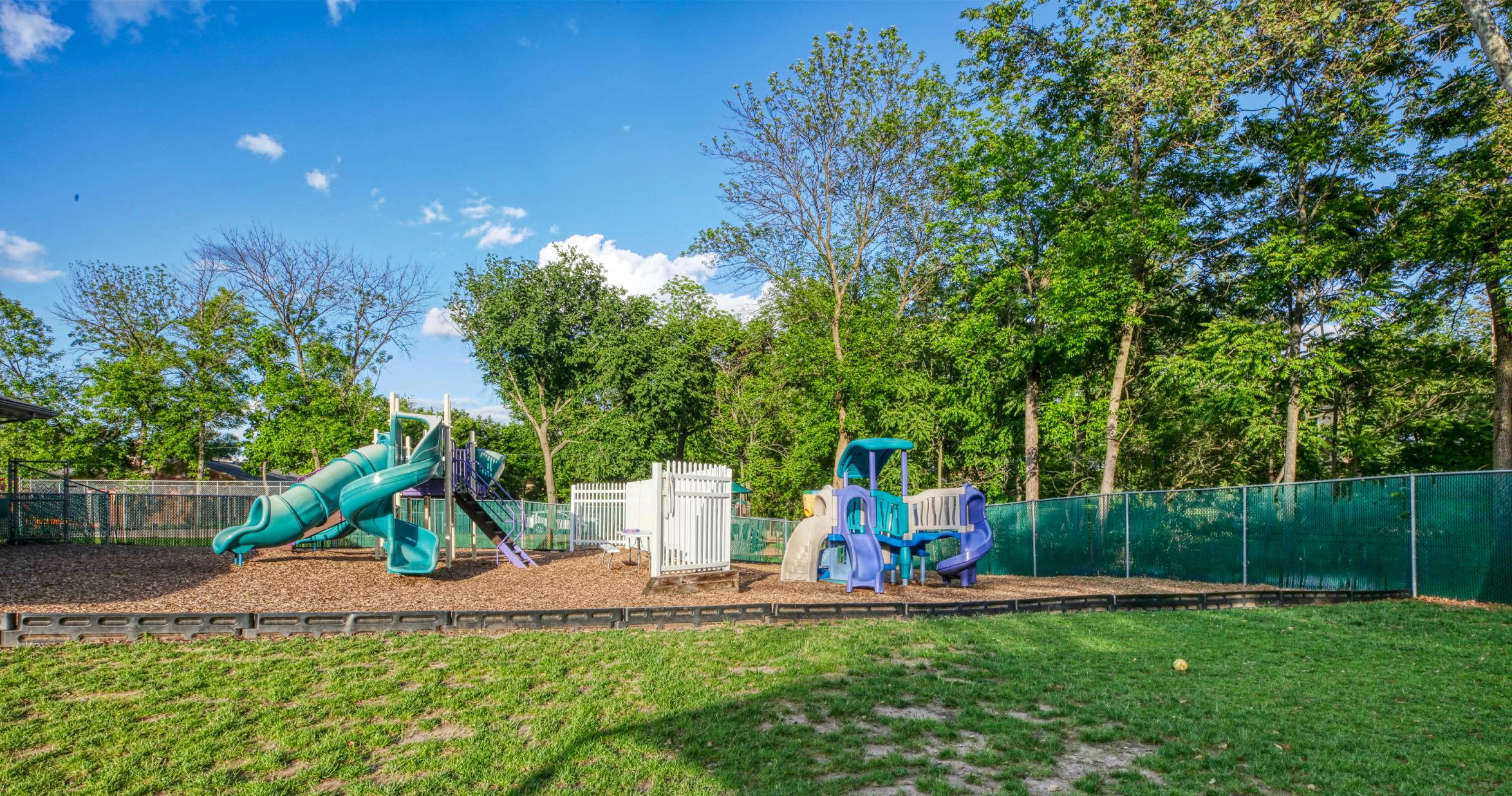 A playground with two main structures featuring slides and climbing areas