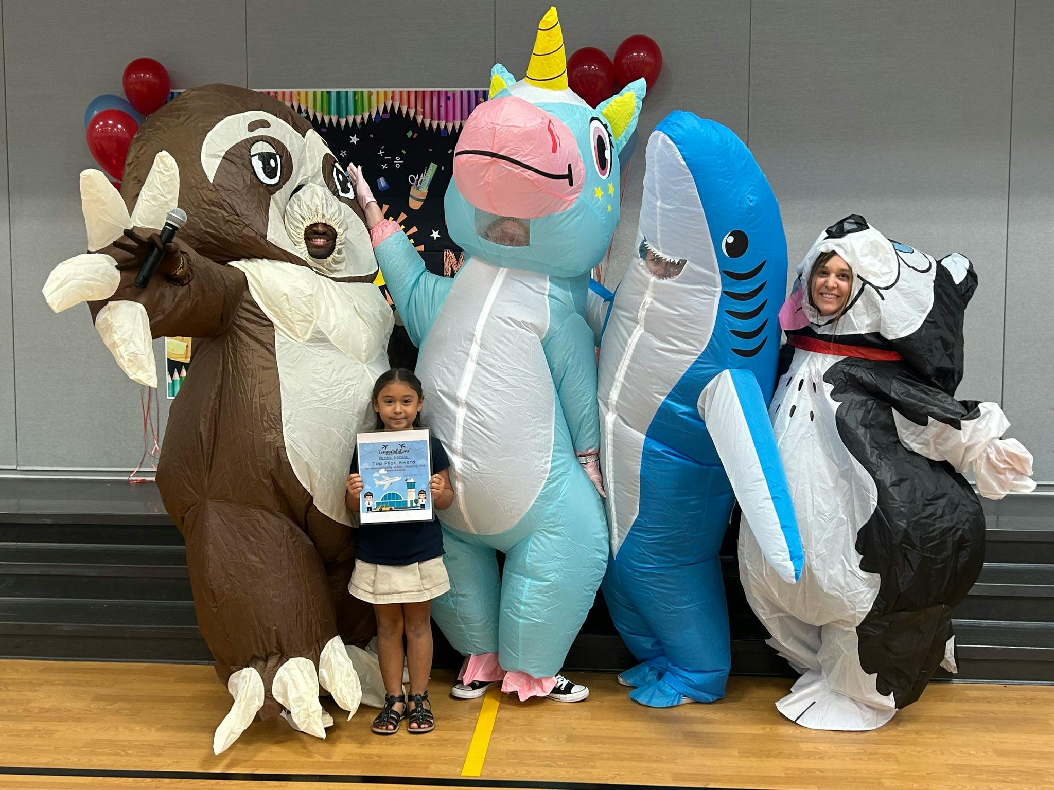 Child holding a book with four people in inflatable animal costumes