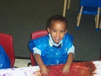 Child in a blue smock finger painting
