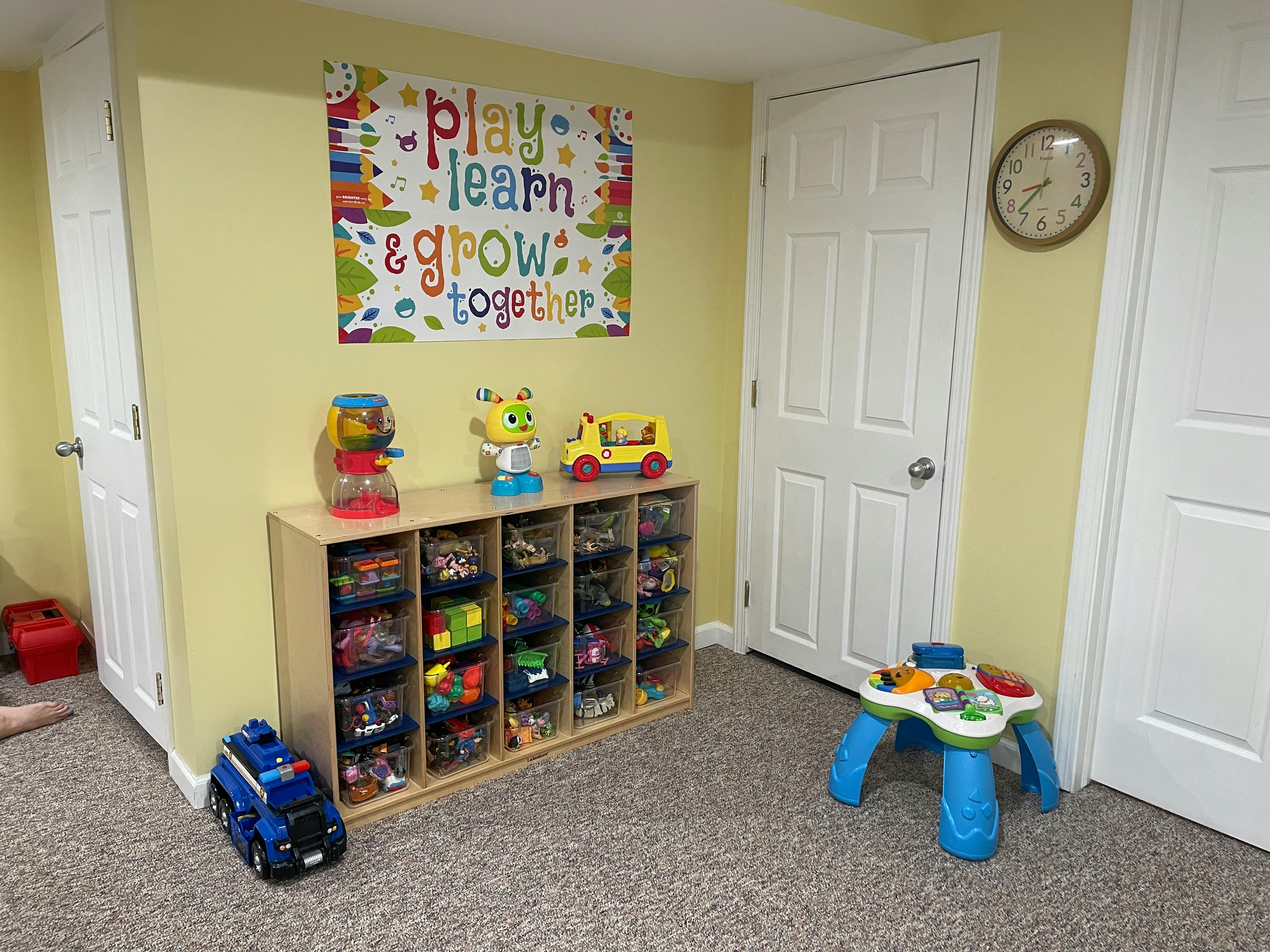 Playroom with toy storage, toys, and a sign that says "play learn & grow together"
