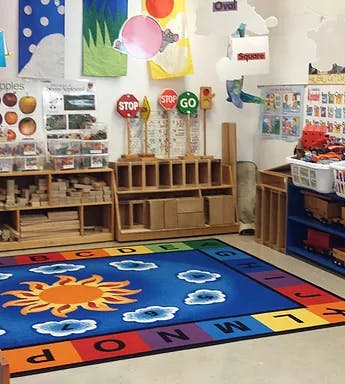 Classroom with a colorful alphabet rug and shelves of learning materials
