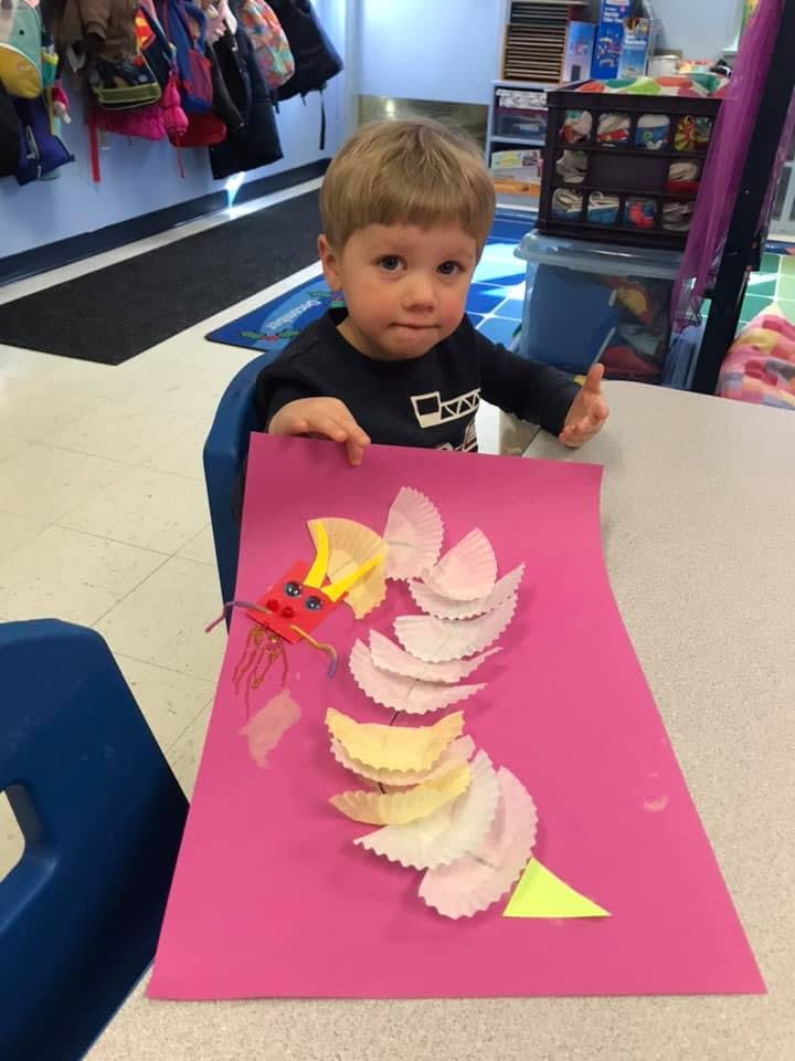Child sitting at a table with a craft project on pink paper