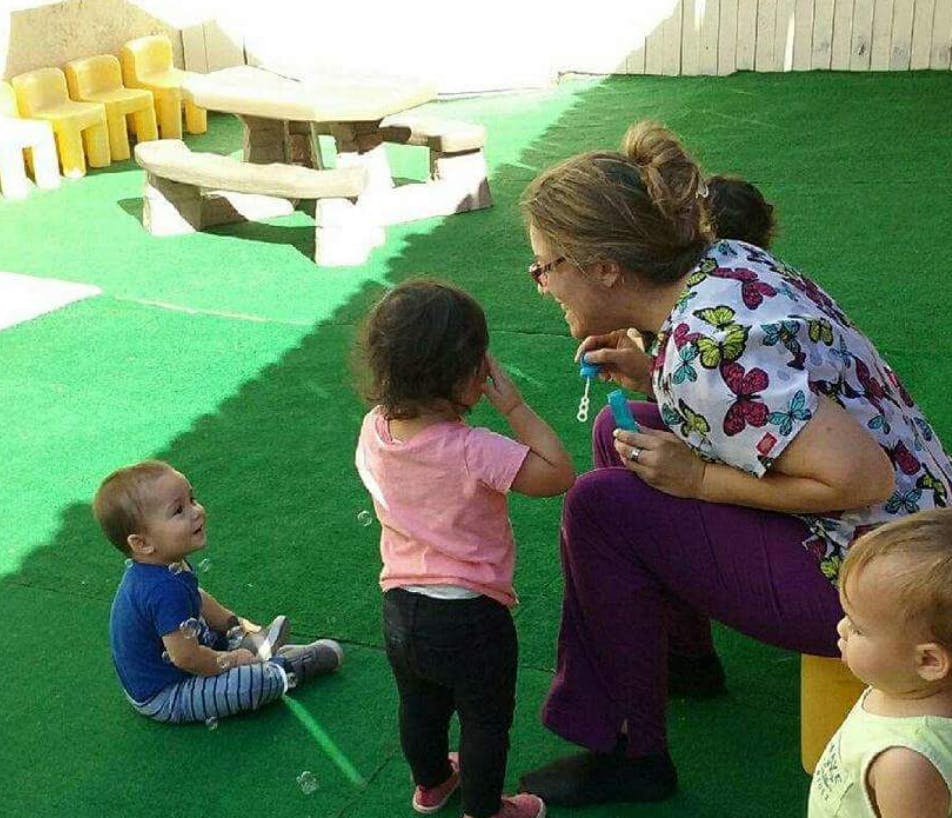 Person blowing bubbles for children on green turf