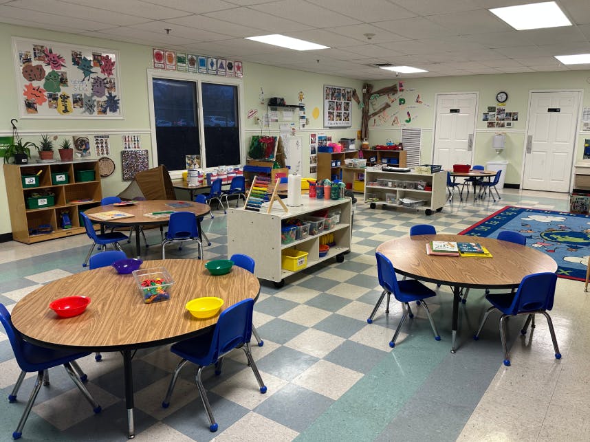 A colorful classroom with multiple small tables and blue chairs