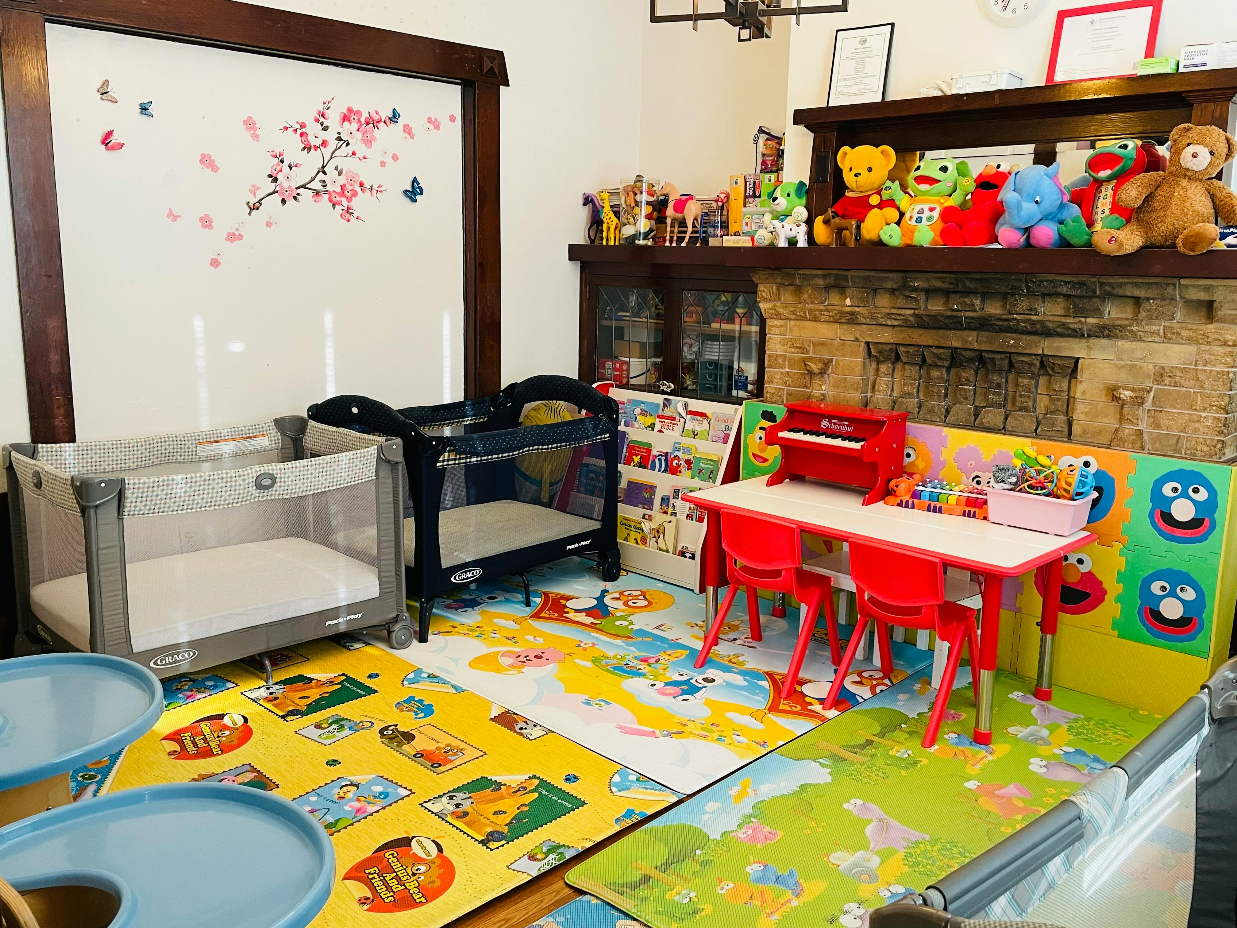 Playroom with two cribs, a small table with chairs, and toys