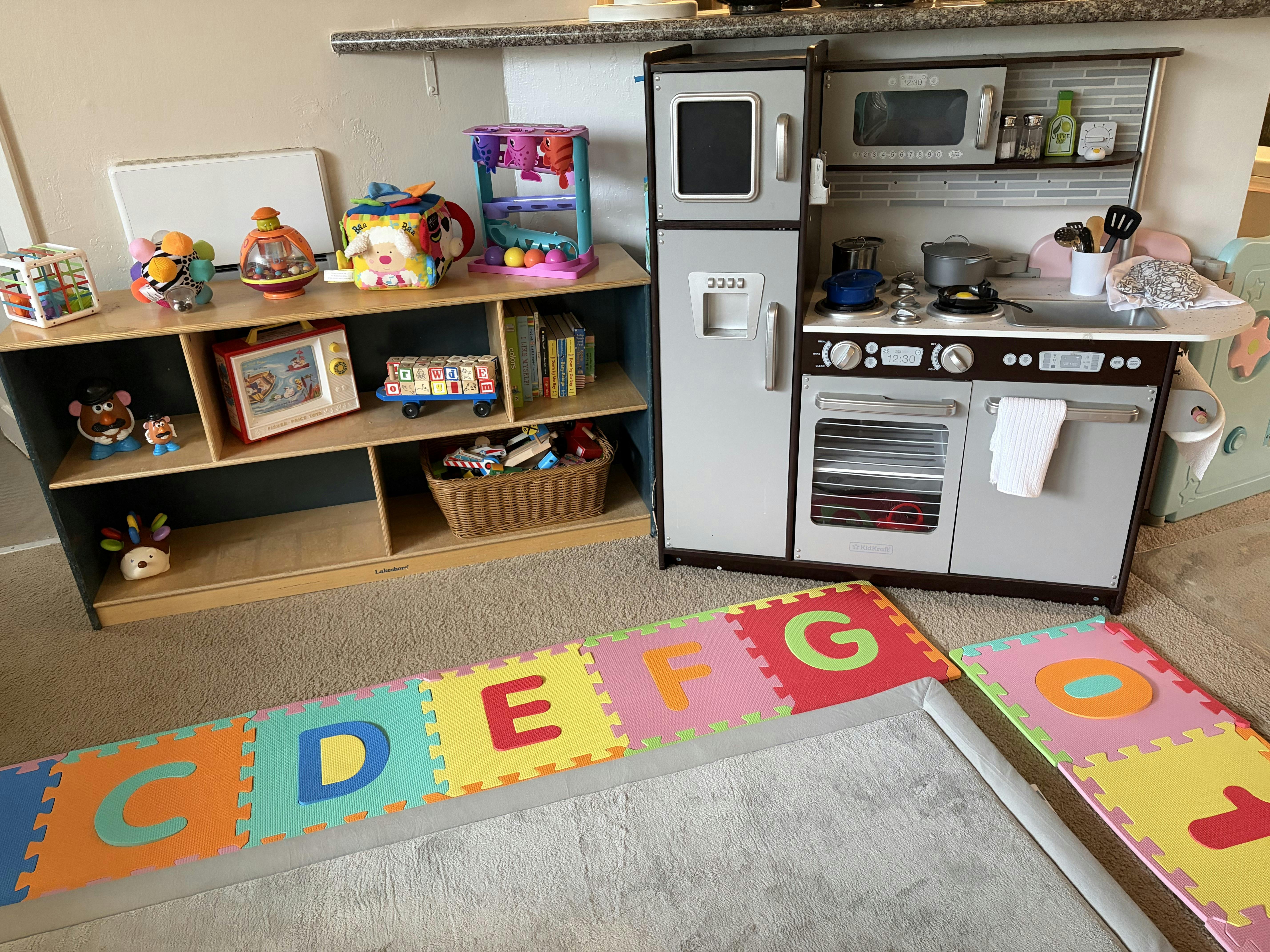 Children's play kitchen and toy shelf with alphabet playmat