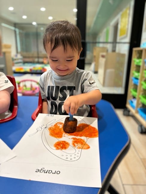 Child using a stamp to paint a butterfly drawing on paper