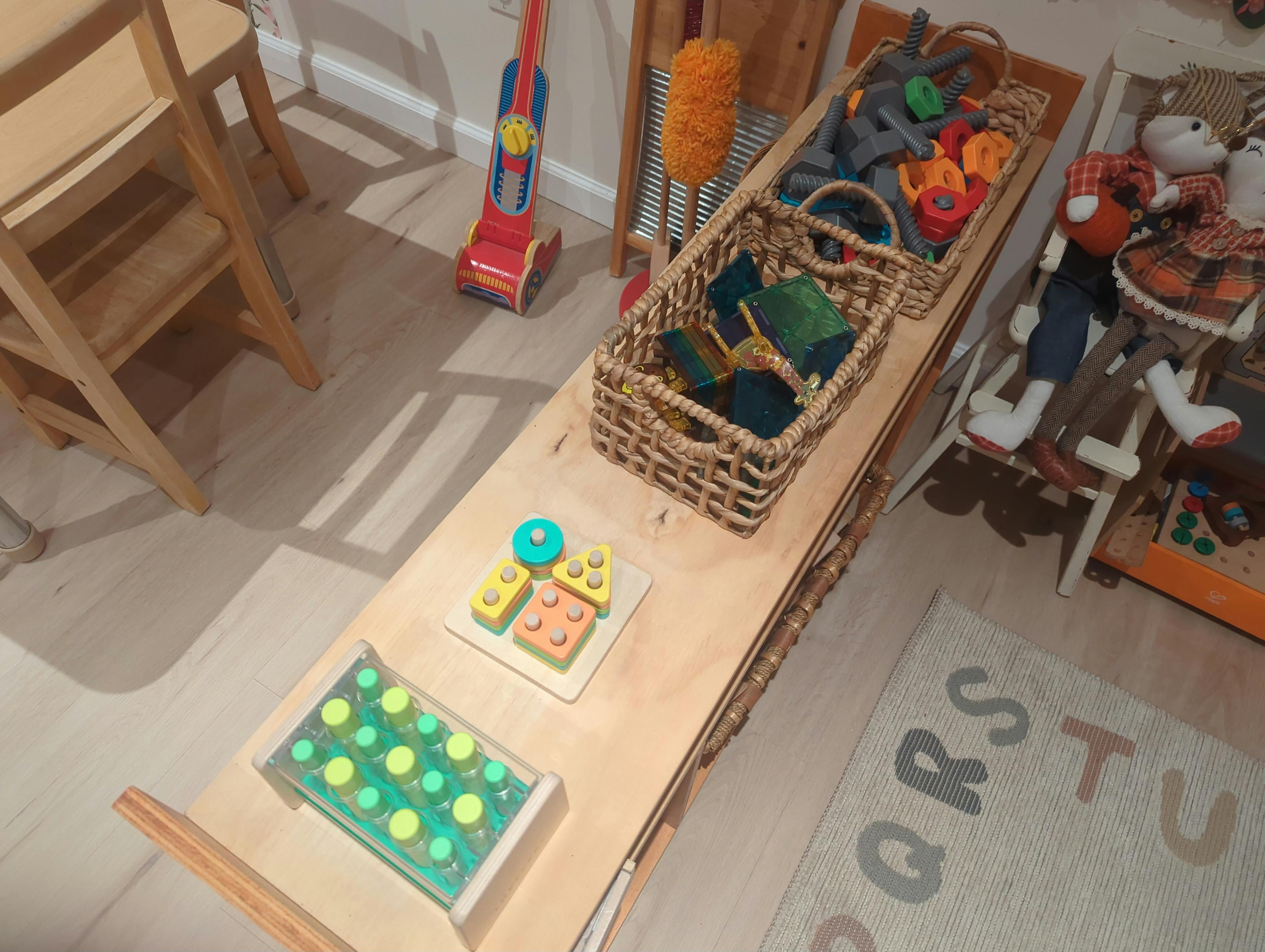 Children's toys arranged on a wooden table, including shape sorters and building blocks
