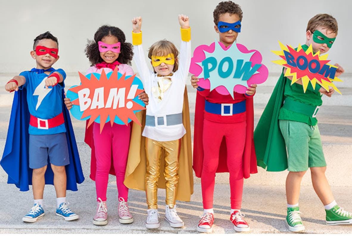 Five children in superhero costumes, two holding signs with “BAM!” and “POW”