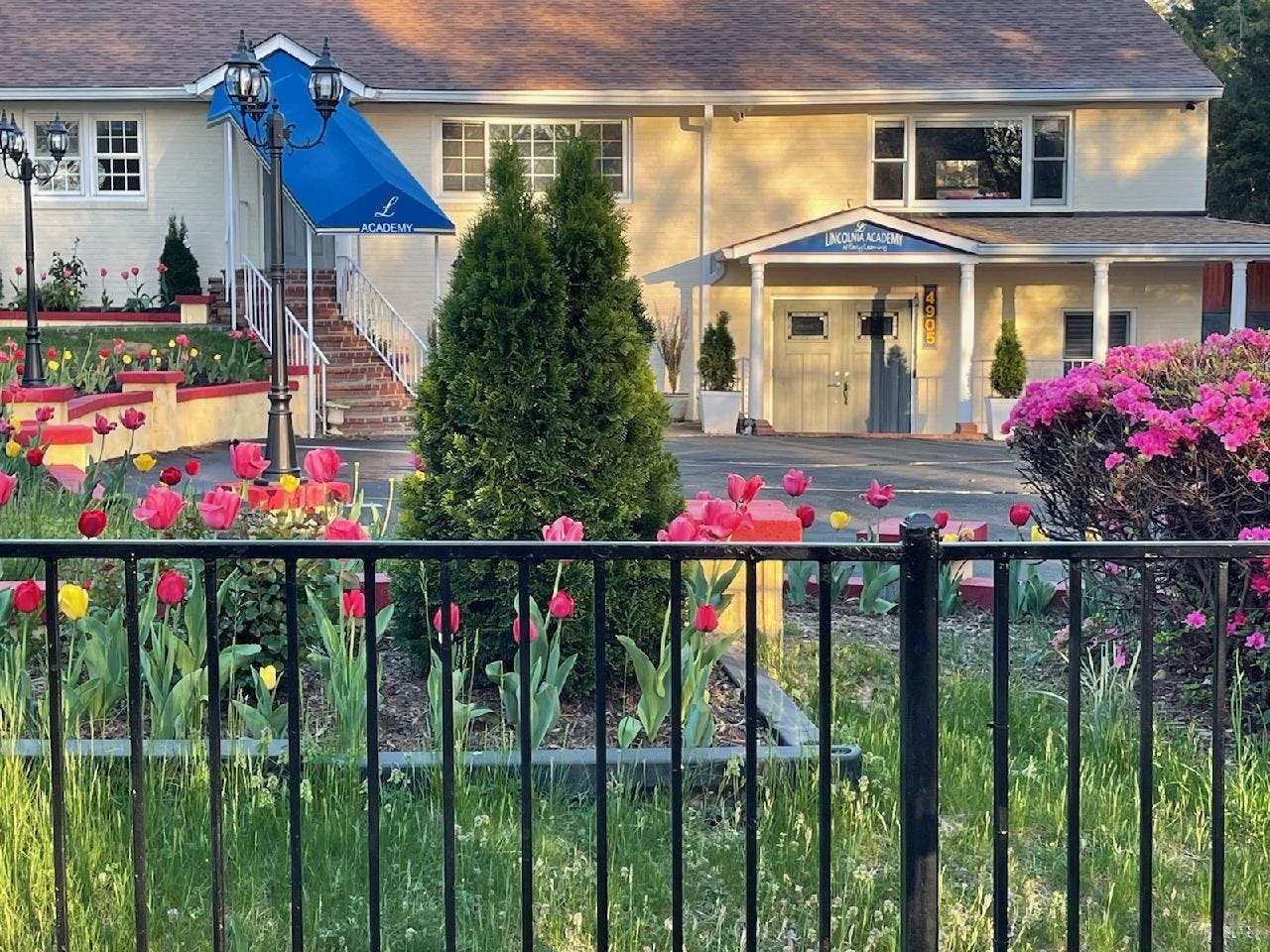 Building exterior with a blue awning, stairs, and flower beds