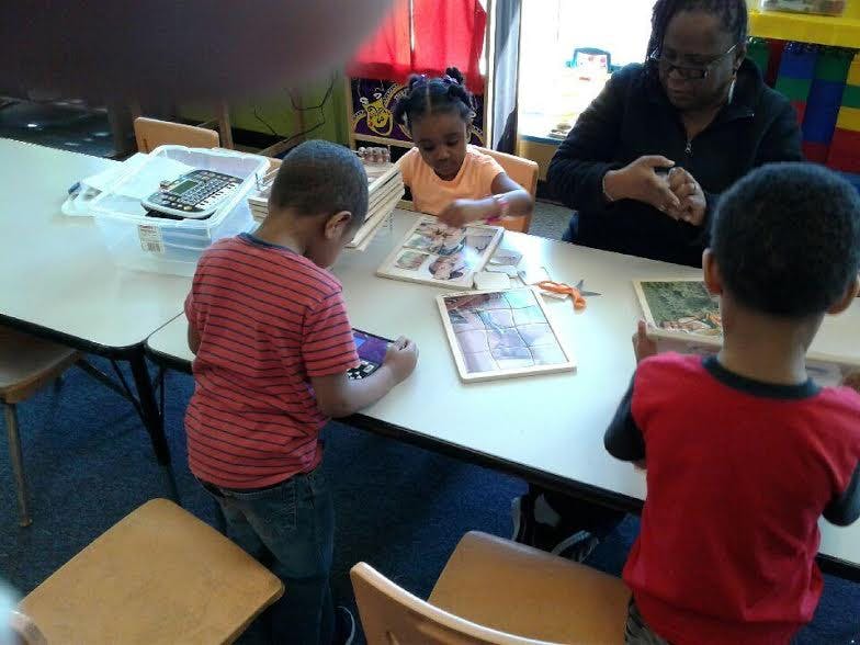 Adult and three children at a table with puzzles