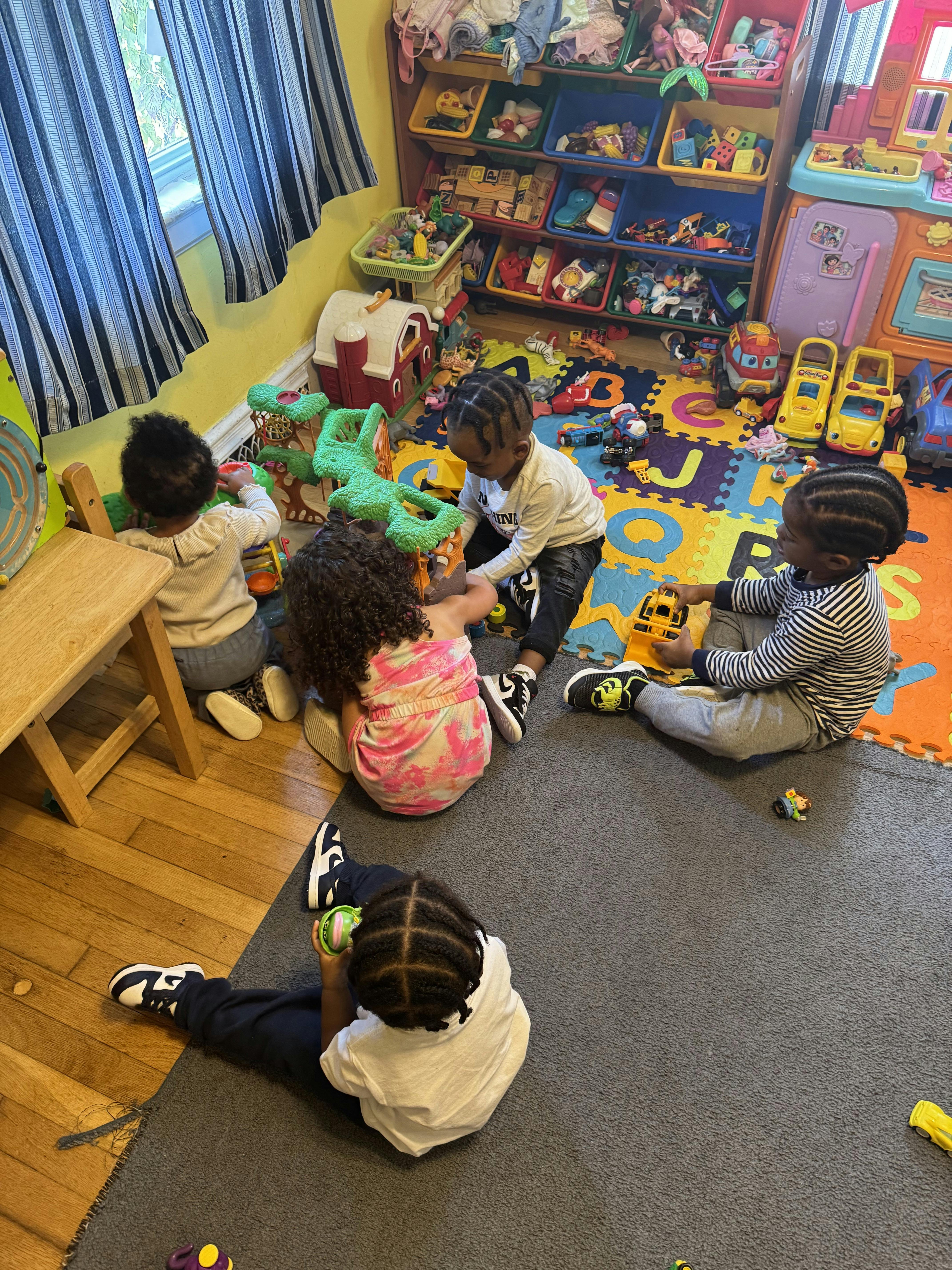 Children playing with toys on a colorful mat in a room