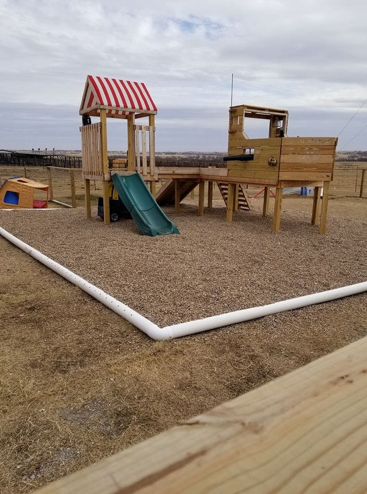 Wooden playground structure with a slide and a red and white striped roof