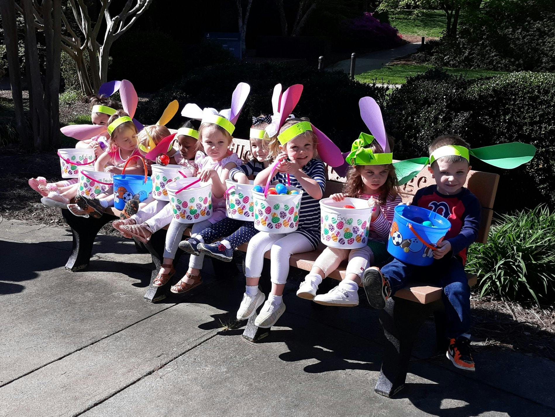 Children wearing bunny ears and holding baskets on to Easter baskets